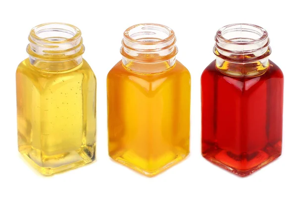 Três garrafas com óleos fechar isolado em branco — Fotografia de Stock