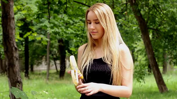 Молода дівчина їсть банан на природі, частина 1 — стокове відео