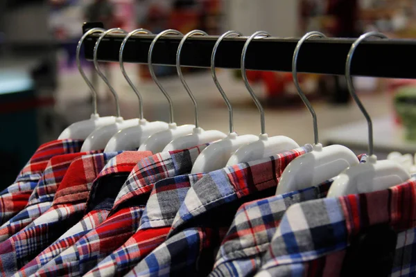 Рубашки на вешалках в магазине — стоковое фото