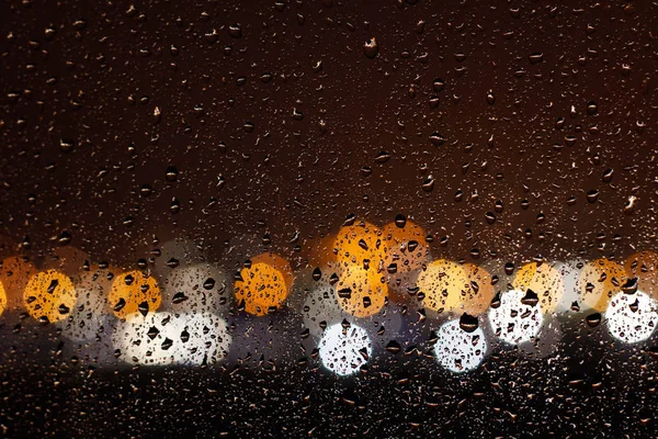 As gotas de chuva descem pelo vidro da janela à noite — Fotografia de Stock