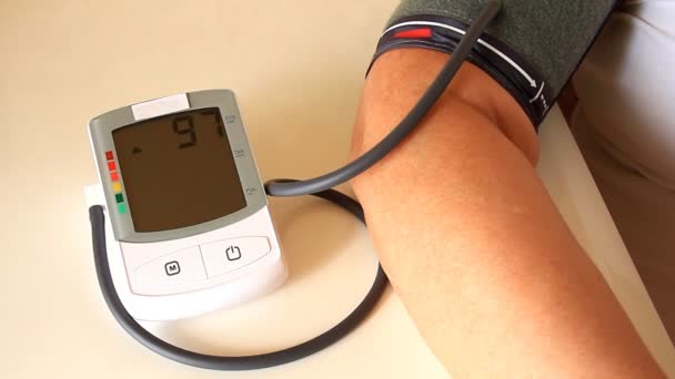 Женщина измеряет артериальное давление с помощью измерительного прибора — стоковое видео