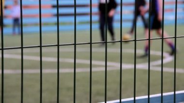 Genç çocuklar öğrenir çekim, defocused futbol oynamak, çit üzerinde odaklan için