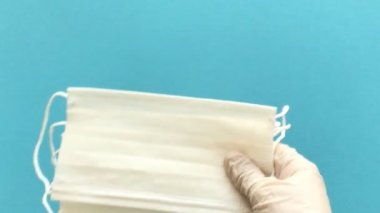 Doktorun elindeki tıbbi eldiven ağız ve burnu kapamak için birkaç tipik tek kullanımlık ameliyat maskesi tutuyor. Anti virüs koruması Coronavirus, COVID-19 ve diğer tehlikeli virüsler. 4K Çözünürlüğü