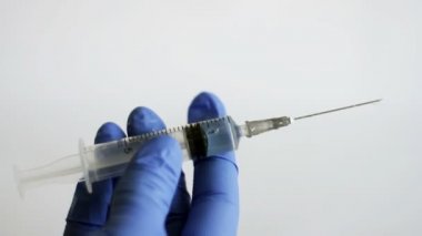 Doktorun elinde mavi tıbbi eldiven var. İçinde enjeksiyona hazır bir şırınga var. Sağlık ve ilaç kavramlarını, anti-virüs koruması Coronavirus, COVID-19 ve diğer tehlikeli virüslerden gelen aşıları ele alalım.