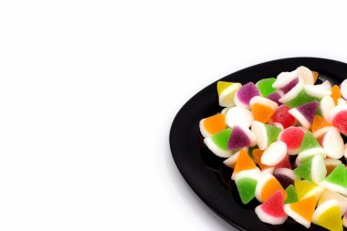 Beyaz arka planda izole edilmiş siyah bir tabakta jöleli şekerler. ve uzayı kopyala.