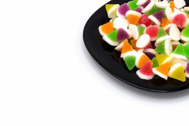 Beyaz arka planda izole edilmiş siyah bir tabakta jöleli şekerler. ve uzayı kopyala.