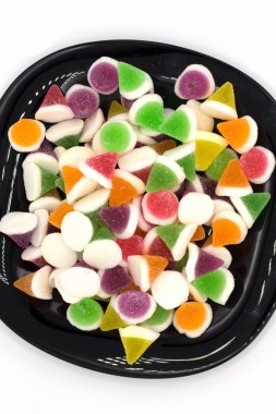 Beyaz arka planda izole edilmiş siyah bir tabakta jöleli şekerler. ve uzayı kopyala.