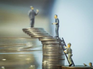 Madeni paraların üzerinde duran minyatür insanlar.