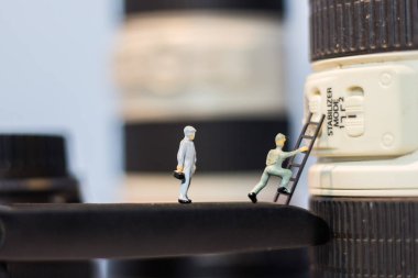 Minyatür insanlar kameranın lenslerini kontrol ediyor..