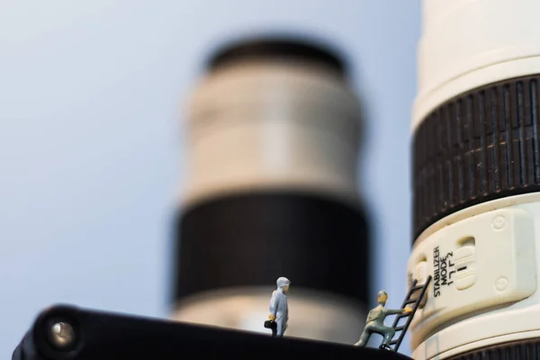Minyatür insanlar kameranın lenslerini kontrol ediyor..