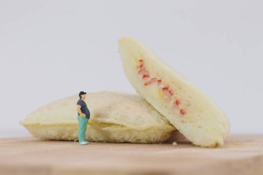 Minyatür insanlar, şişman adam beyaz arka planda ton balığı mayonezine ve yengeç saplı mayoneze bakıyor.