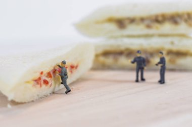 Minyatür insanlar beyaz arka planda sandviç ekmeğinin kalitesini kontrol eder