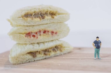 Minyatür insanlar, şişman adam beyaz arka planda ton balığı mayonezine ve yengeç saplı mayoneze bakıyor.