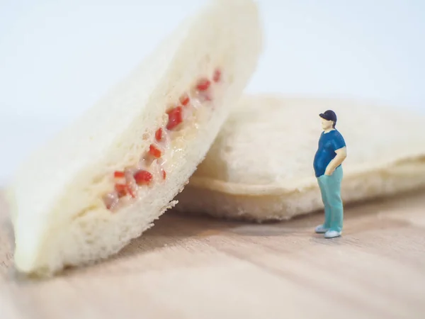 Miniature people, Fat man looks at tuna mayonnaise and crab sticks mayonnaise on white background