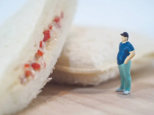 Miniature people, Fat man looks at tuna mayonnaise and crab sticks mayonnaise on white background