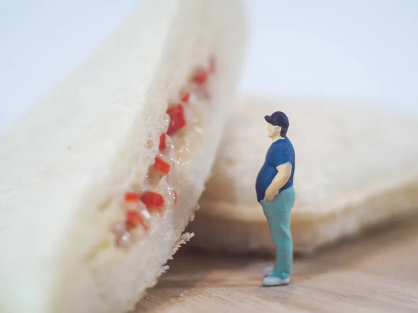 Miniature people, Fat man looks at tuna mayonnaise and crab sticks mayonnaise on white background