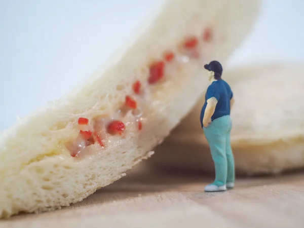 Miniature people, Fat man looks at tuna mayonnaise and crab sticks mayonnaise on white background