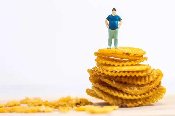 Minyatür insanlar, beyaz arka planda patates cipsi üzerinde duran şişman adam (yiyecek kavramı))