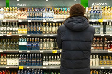 Yekaterinburg, Rusya - Kasım 2019. Markette içki sıralarının önünde duran bir adam. Alıcı ürünü seçer..