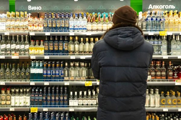 Jekaterynburg, Rosja - listopad 2019. Mężczyzna przed rzędami alkoholu na targu. Kupujący wybiera produkt. — Zdjęcie stockowe