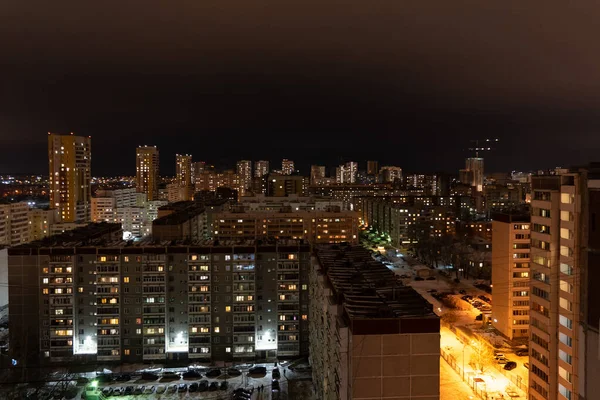 Жилой район в зимнюю ночь. Светящиеся окна многоэтажных жилых домов. Много припаркованных машин во дворах — стоковое фото