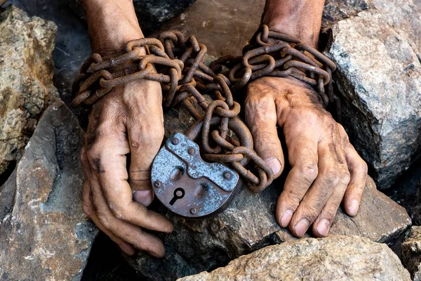Las manos humanas están encadenadas. Gran castillo de hierro viejo. Grandes piedras grises. Las manos finas y sucias de un esclavo envuelto en una vieja cadena oxidada . —  Fotos de Stock