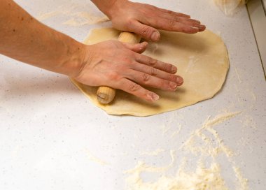 Mangırı çıkar. Fırıncı hamuru ahşap mutfak masasına serpiştirir.