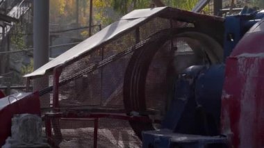 Taş ezicinin büyük çarkı dönüyor. Kemer sürücüsü elektrikli motordan dönme dolaba. Taş Ezici Taşları Kırıyor ve Farklı Boyutlarda Parçalara Bürüyor.