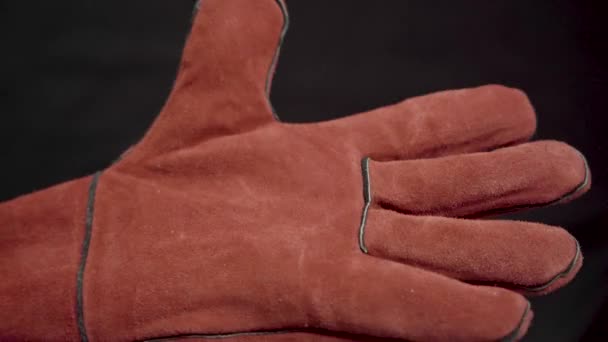 ラフなスエードで作られた大きな作業新しい手袋 特殊溶接手袋 作業用手袋を着用する 暗い背景に男の手を閉じる — ストック動画