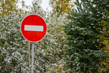 Yol yukarı. Karlı ağaçların arka planında yasaklı kırmızı yol işareti.