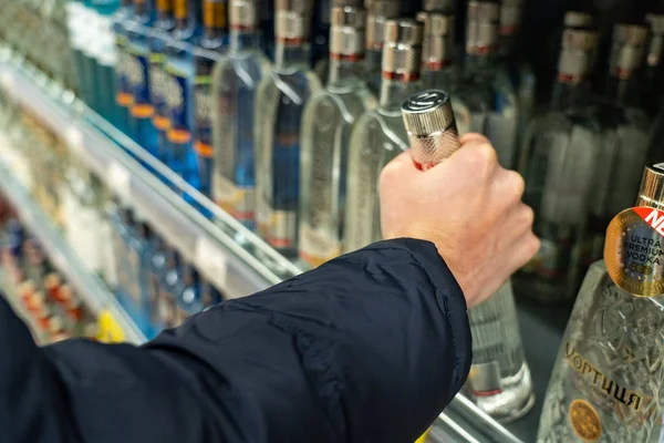 Yekaterinburg, Rusland - november 2019. Rijen van flessen in de alcoholafdeling van de supermarkt en het kiezen van sterke dranken, het nemen van wodka van de plank. Koper koopt alcohol in een supermarkt — Stockfoto