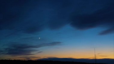 Günbatımından sonra alacakaranlık. Mavi gökyüzüne karşı genç bir ay. Bulutların pürüzsüz hareketi. Zaman aşımı.