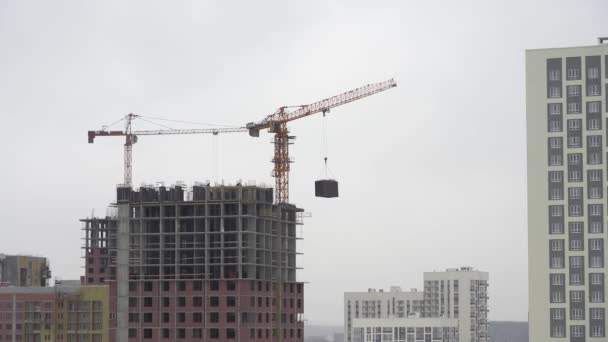 Yekaterinburg, russland - november 2019. ein baukran hebt eine last. Turmdrehkran auf einer Baustelle hebt eine Last am Hochhaus. der Prozess des Baus eines mehrstöckigen modernen — Stockvideo