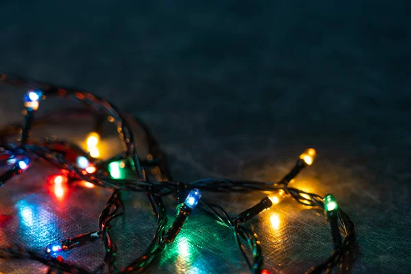 Színes izzók világítanak az asztalon a sötétben. Másold a helyet. Ragyogó karácsonyi lámpák az asztalon, közelkép — Stock Fotó