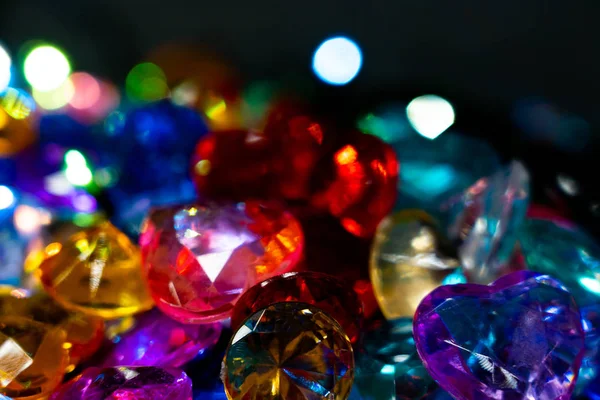 Multi-colored glass pebbles glow in the dark with bright saturated colors. Close-up. Multi-colored faceted glass stones