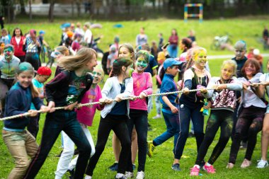 Chelyabinsk Bölgesi, Rusya - Temmuz 2019. Farklı milletlerden çocuklar renk festivalinde arkadaşlar. Halat çekme. Çocuklar oyuna tutkuyla bağlıdır. Çocukların yüzünde canlı duygular
