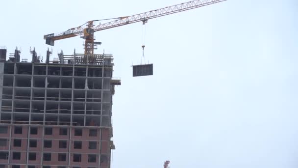 Yekaterinburg, russland - november 2019. ein baukran hebt eine last. Turmdrehkran auf einer Baustelle hebt eine Last am Hochhaus. der Prozess des Baus eines mehrstöckigen modernen — Stockvideo