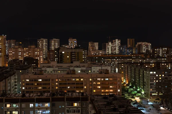 Zonas residenciales en una noche de invierno. Ventanas brillantes de edificios residenciales de varios pisos. Muchos coches aparcados en los patios —  Fotos de Stock