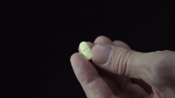 黒の背景に1本の錠剤を保持している男性の手のクローズアップ — ストック動画