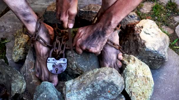 監禁された男鉄の鎖の奴隷は自分自身を解放しようとしている 奴隷の人生からのシーン 奴隷労働の象徴 鎖に手と足鎖を壊す第二の選択肢 — ストック動画