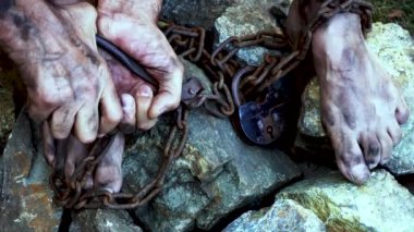 Tutsak bir adam. Demir zincirli bir köle kendini kurtarmaya çalışıyor. Bir kölenin hayatından bir sahne. Köle işçiliğinin sembolü. Eller ve ayaklar zincirli. Zincirler kırılıyor.