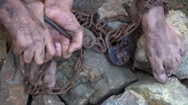 監禁された男鉄の鎖の奴隷は自分自身を解放しようとしている 奴隷の人生からのシーン 奴隷労働の象徴 鎖に手と足鎖の切断 — ストック動画
