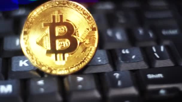Golden sparkling bitcoin glides on a black keyboard background — 비디오