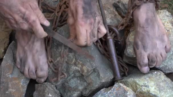 Tempat kerja budak. Tangan dan kaki seorang budak diikat dengan rantai besi. Sebuah upaya untuk membebaskan diri dari perbudakan. Mematahkan rantai . — Stok Video