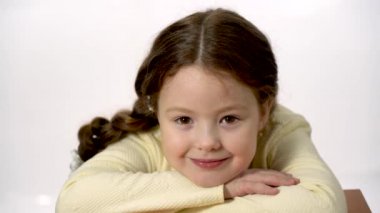 Cute girl 5-6 years old looking at the camera and smiling. Closeup portrait on a white background.