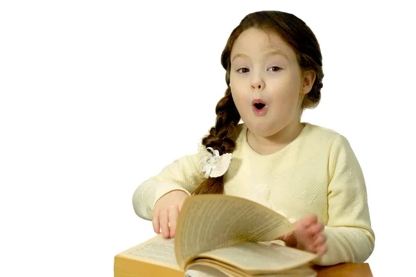 Surpreendido bebê bonito com um livro segurando a boca aberta. Menina de cinco ou seis anos isolada em branco — Fotografia de Stock