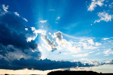 Bulutların arasından geçen güneş ışınları. Bulutlar ve mavi bir gökyüzü.