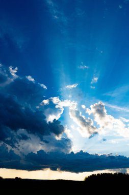 Bulutların arasından geçen güneş ışınları. Bulutlar ve mavi bir gökyüzü.