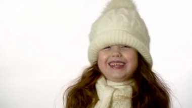Little girl in a white knitted hat. Beautiful little girl in cap and scarf isolated on white.