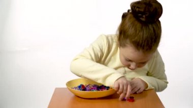 A preschooler learns to count objects. 6-year-old girl plays with colored stones.